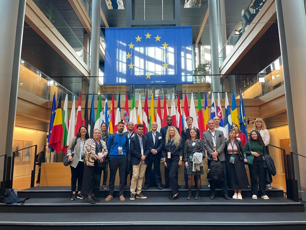 Parisen kymmentä ihmistä seisoo Euroopan Parlamentissa Strasbourgissa Euroopan maiden lippujen edessä. Taustalla eri maiden liput sekä iso EU-lippu.