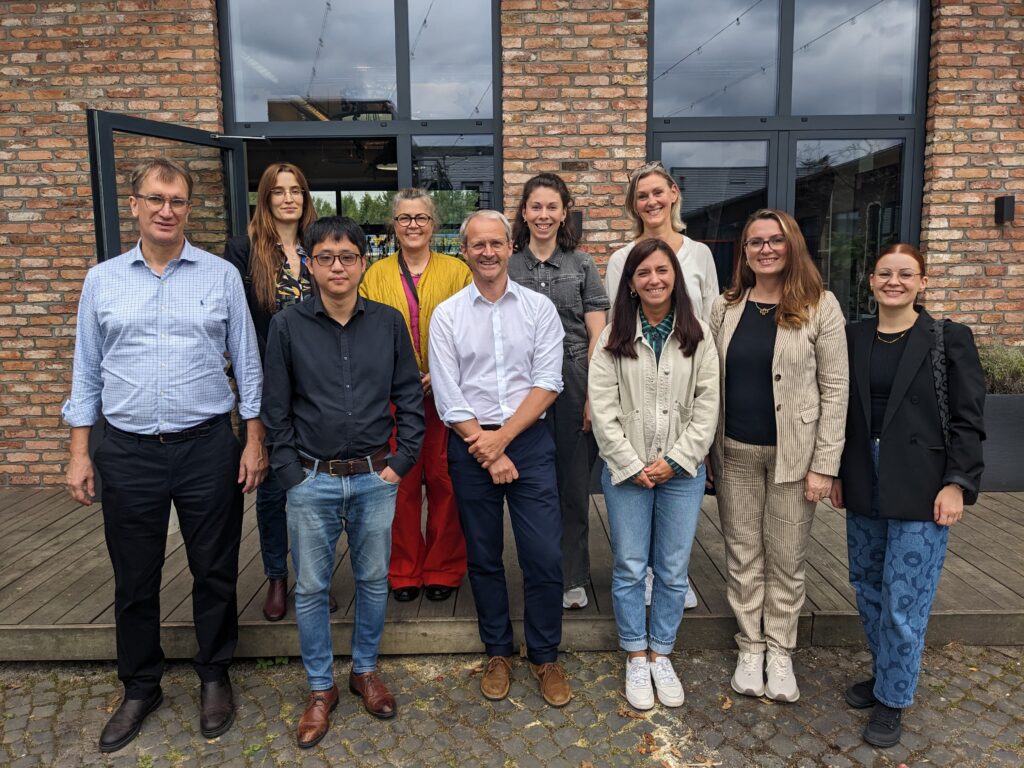 A group of ten people standing in front of a brown tiled building